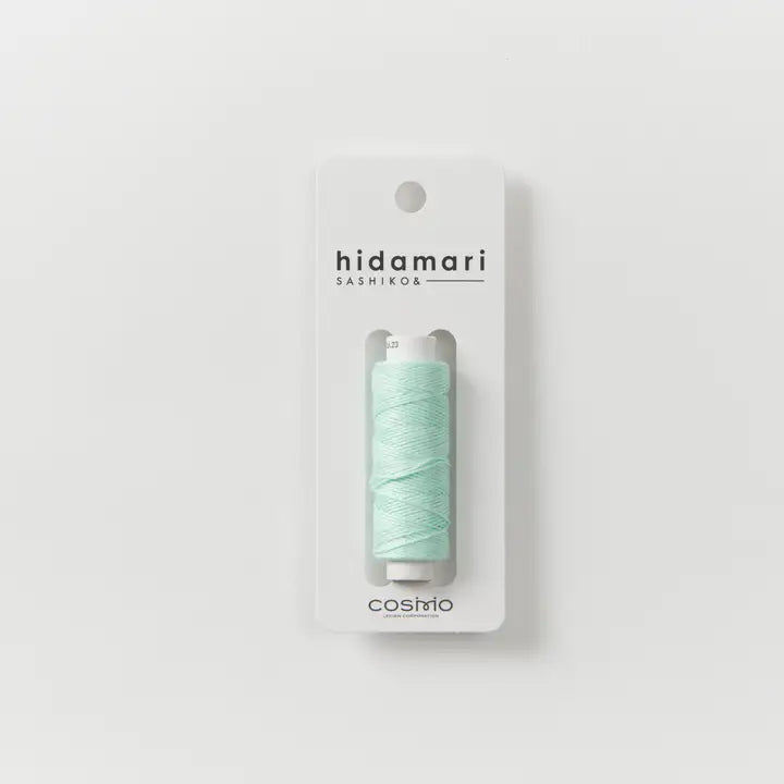 Mint green thread spool in packaging with 'hidamari sashiko' branding on a light gray background