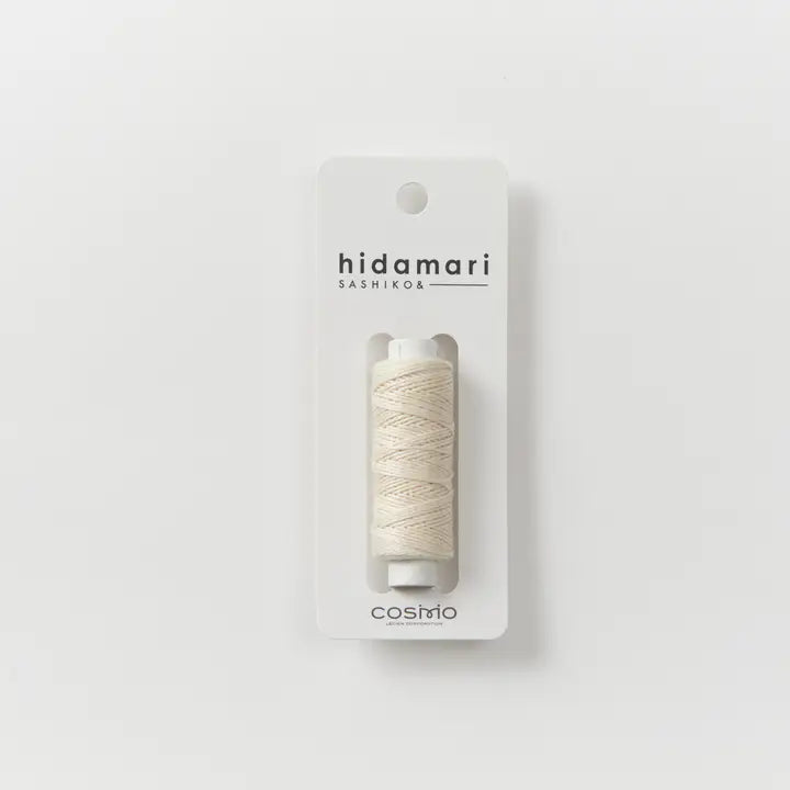 Spool of beige thread in packaging with 'hidamari sashiko' branding on a white background