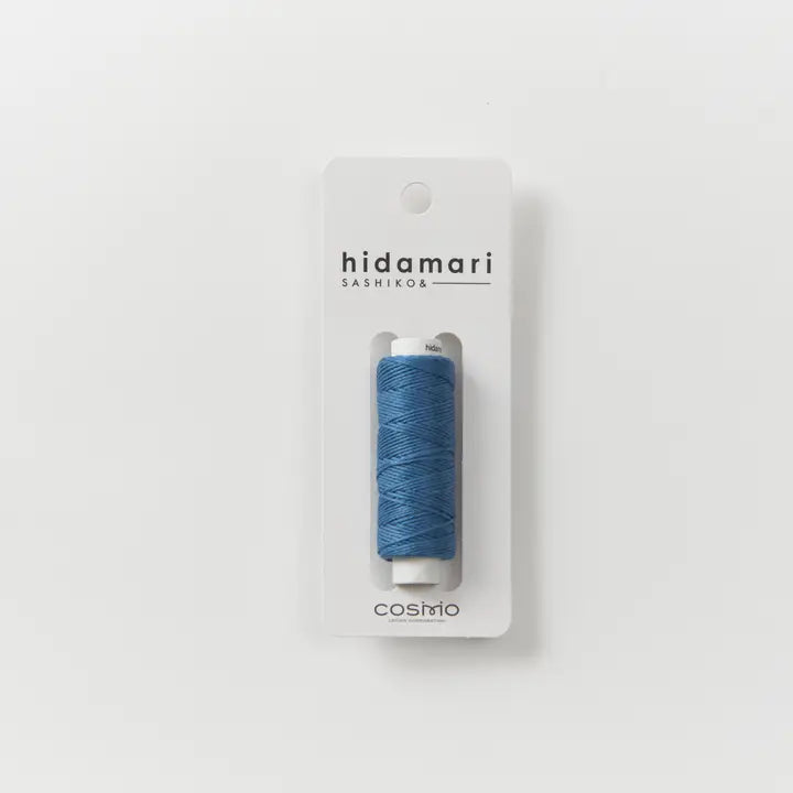 Blue thread spool on a 'hidamari sashiko' package against a white background